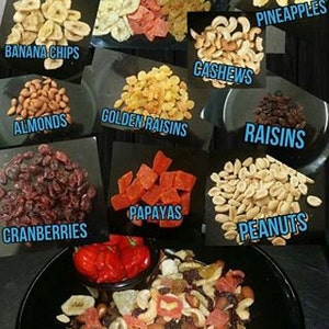May include: A bowl of trail mix containing a variety of dried fruits, nuts, and seeds. The mix includes banana chips, almonds, cashews, golden raisins, cranberries, papayas, peanuts, and pineapples. The mix is labelled "Blazing Dragon Spicy Tropical Trail Mix".