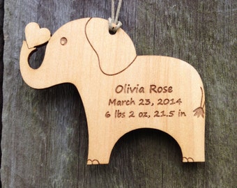 Könnte beinhalten: Holz-Elefanten-Anhänger mit einem Herzen im Rüssel. Er ist mit dem Namen "Olivia Rose", dem Datum "March 23, 2014" und den Geburtsdaten "6 lbs 2 oz, 21.5 in" graviert.