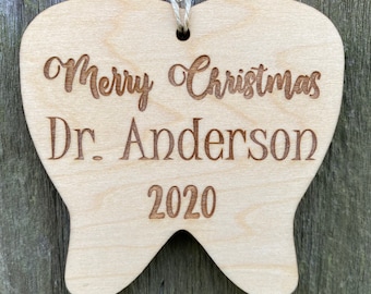 May include: A wooden tooth-shaped Christmas ornament with the text "Merry Christmas Dr. Anderson 2020" engraved on it.