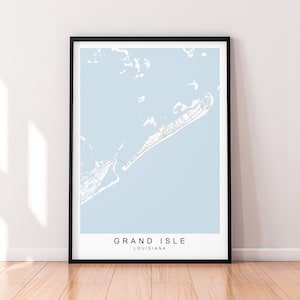 May include: A black framed print of a map of Grand Isle, Louisiana. The map is on a light blue background and shows the island's coastline and roads. The text "GRAND ISLE" and "LOUISIANA" is printed below the map.
