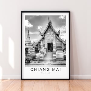 May include: Black and white photograph of a traditional Thai temple with intricate carvings and a large, ornate entrance. The temple is surrounded by lush greenery and a stone staircase leads up to the entrance. The text "CHIANG MAI THAILAND" is printed below the image.