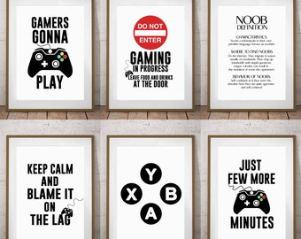 May include: Six black and white printable wall art prints with gamer-themed text and graphics. The prints feature phrases like "Gamers Gonna Play", "Keep Calm and Blame It On The Lag", and "Just Few More Minutes".