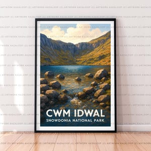 May include: A framed print showcasing a landscape of Cwm Idwal in Snowdonia National Park. The artwork depicts a tranquil lake surrounded by mountains and rocks, with the text "CWM IDWAL SNOWDONIA NATIONAL PARK" at the bottom.