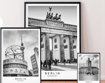 May include: Three black and white framed prints of Berlin landmarks. The top print shows the Brandenburg Gate with a statue of a chariot pulled by four horses. The middle print shows the Berlin Clock with a large globe and the text "BERLIN GERMANY". The bottom print shows the Berlin Palace with the text "BERLIN GERMANY".