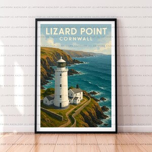 May include: Framed art print of Lizard Point, Cornwall, featuring a white lighthouse and buildings on a cliff overlooking the sea. The artwork shows a sunny day with blue water and green cliffs. The text "Lizard Point Cornwall" is at the top.