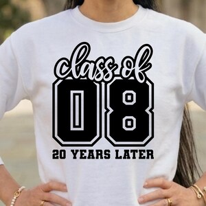 May include: A white long-sleeve sweatshirt featuring a black graphic print on the chest. The design includes the text "class of" in a cursive font above the large block numbers "08" and the text "20 YEARS LATER" in a bold sans-serif font.