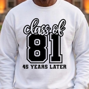 May include: A white long-sleeve crewneck sweatshirt featuring a black graphic print on the chest. The text reads "class of 81" in a script font above large block numbers "81" and the text "45 YEARS LATER" in a bold sans-serif font below.