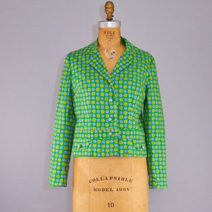 May include: A green and blue polka dot blazer with a button closure. The blazer has a cropped length and a collar.