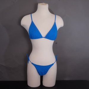 May include: A blue polka dot bikini top and bottom. The top is a triangle style and the bottom is a tie-side style.