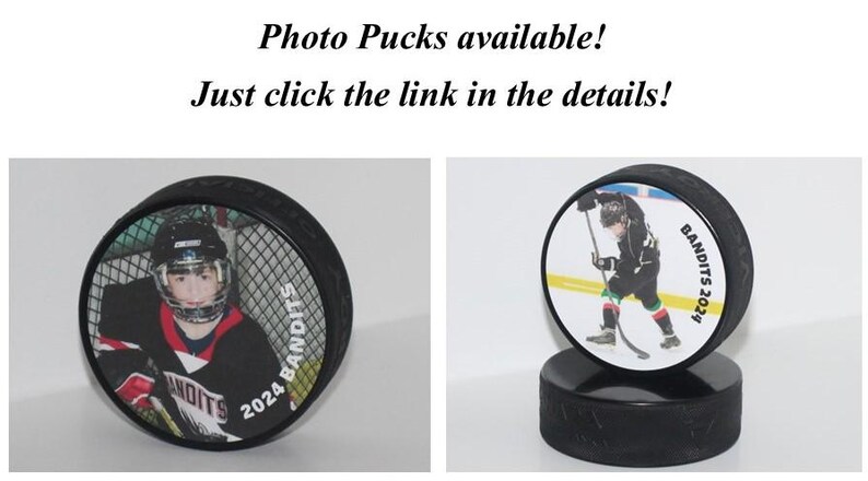 May include: Two hockey pucks with personalized photos and the text "BANDITS 2024" printed on them. The pucks are on a black base.