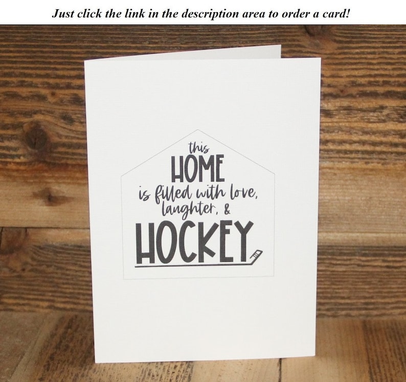 May include: A white card with black text that reads "this HOME is filled with love, laughter, & HOCKEY". The text is in a house shape with a hockey stick underneath.