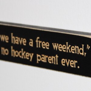 May include: Black wooden sign with white text that reads "Wow, we have a free weekend," said no hockey parent ever."
