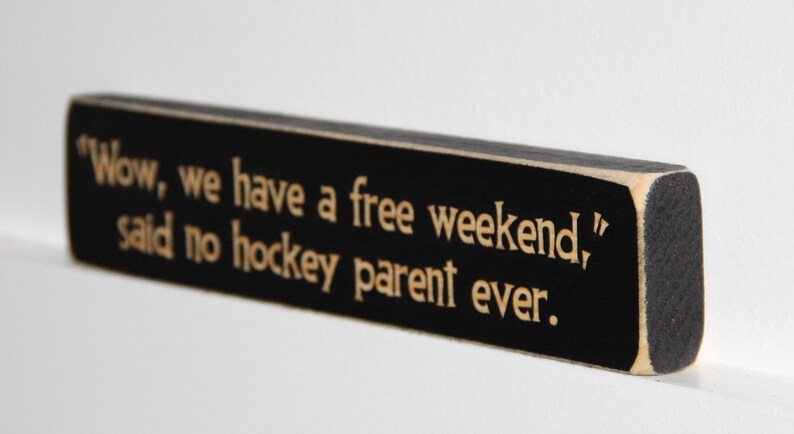 May include: Black wooden sign with white text that reads "Wow, we have a free weekend," said no hockey parent ever."