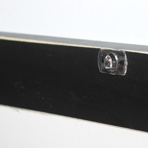 May include: Black wooden sign with two clear plastic hanging hooks on the back.