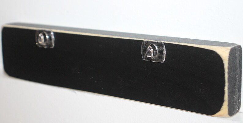 May include: Black wooden sign with two clear plastic hanging hooks on the back.