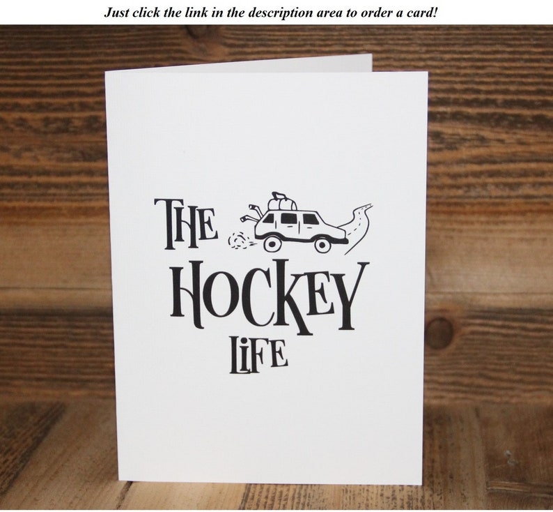 May include: A white card with black text and a simple illustration of a car with hockey sticks on top. The text reads "THE HOCKEY LIFE".