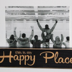 May include: Black wooden picture frame with the text "this is my Happy Place" in gold lettering. The frame holds a black and white photo of people cheering at a sporting event.