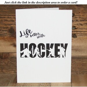 May include: A white card with black text that reads "Life is better with HOCKEY". The word "HOCKEY" is made up of hockey players in silhouette.