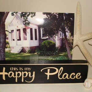 May include: Black wooden sign with white lettering that reads "this is my Happy Place". The sign is sitting on a table with a seashell and a starfish.
