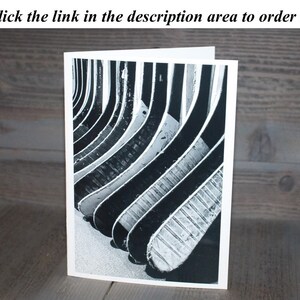 May include: Black and white photograph of a stack of hockey sticks, arranged in a pattern, with the grain of the wood visible.