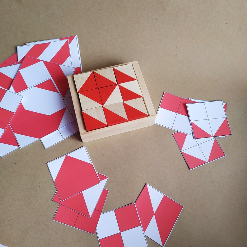 Puede incluir: Una caja de madera con un patr&oacute;n geom&eacute;trico rojo y blanco hecho de peque&ntilde;os bloques de madera. La caja est&aacute; abierta y los bloques son visibles. Tambi&eacute;n hay varias formas geom&eacute;tricas rojas y blancas sobre una superficie marr&oacute;n.
