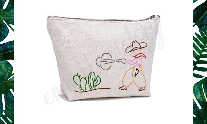 May include: A white canvas zippered pouch with an embroidered design of a cowboy shooting a gun with a cloud of smoke behind him. The cowboy is wearing a brown hat, a pink shirt, and brown trousers. There are green cacti in the foreground.