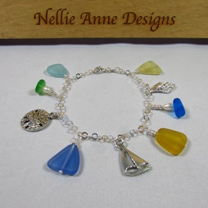 May include: A silver charm bracelet with sea-themed charms, including a sailboat, seashells, sand dollars, and sea glass in shades of blue, green, and yellow.