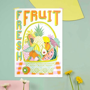 May include: A white poster with the text "FRESH FRUIT" in green, yellow, and orange letters. The poster features a basket overflowing with a variety of fruits, including a pineapple, watermelon, papaya, grapes, and figs. The basket is sitting on a pink and white checkered tablecloth.