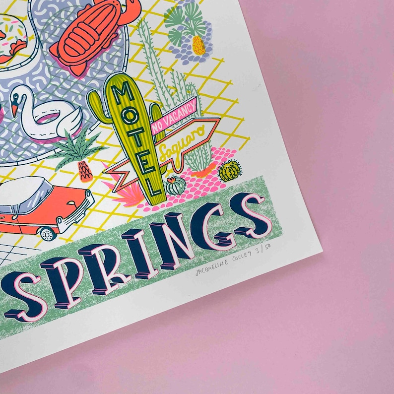 May include: A green and blue illustration of a desert town with the text "Springs" in large, bold letters. The illustration includes a motel sign, a swimming pool, a car, and cacti. The text "Jacqueline Colley 3/50" is in the bottom right corner.