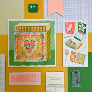 Puede incluir: Una impresión verde y amarilla de una caja de cerillas con un diseño de corazón y flecha. El texto "TRUE LOVE" y "TRADE MARK" está en la caja de cerillas. La impresión está rodeada por un borde verde.