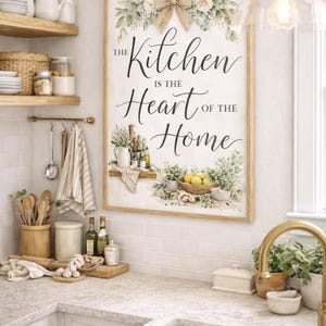 Könnte beinhalten: Ein gerahmtes Küchenschild mit dem Text "The Kitchen is the Heart of the Home". Das Schild ist mit floralen und Schleifenakzenten verziert. Die Küchenszene umfasst Holzregale, Utensilien und ein Waschbecken.