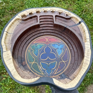 May include: A wooden bowl with a stained glass design in the centre. The bowl is carved to resemble a stadium or arena. The bowl is made of light and dark wood.