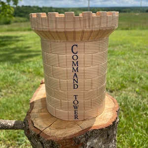 May include: A wooden tower with a castle-like top. The tower is light brown and has the words "COMMAND TOWER" printed on the side.