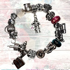 May include: A silver charm bracelet with a variety of charms, including a house, a train, a star, a number 40, and a heart. The charms are all silver and have a detailed design.