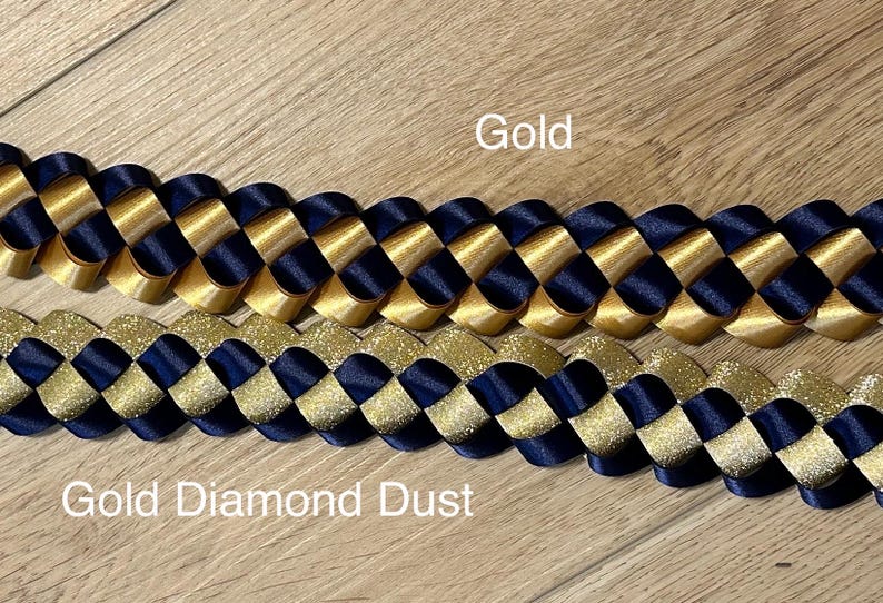 Pu&ograve; includere: Due collane intrecciate, una dorata e una dorata con polvere di diamanti, entrambe con nastro blu scuro.