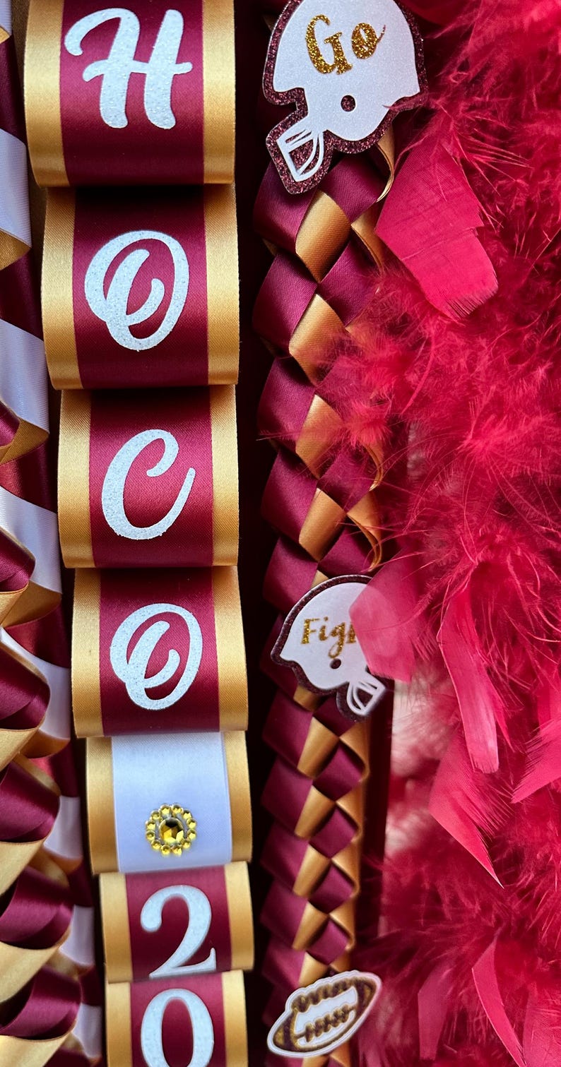 Pu&ograve; includere: Un lei di laurea color granata e oro con lettere bianche che compongono la scritta "HOOO 20" e ciondoli a forma di casco da football. Il lei &egrave; decorato con piume rosse.