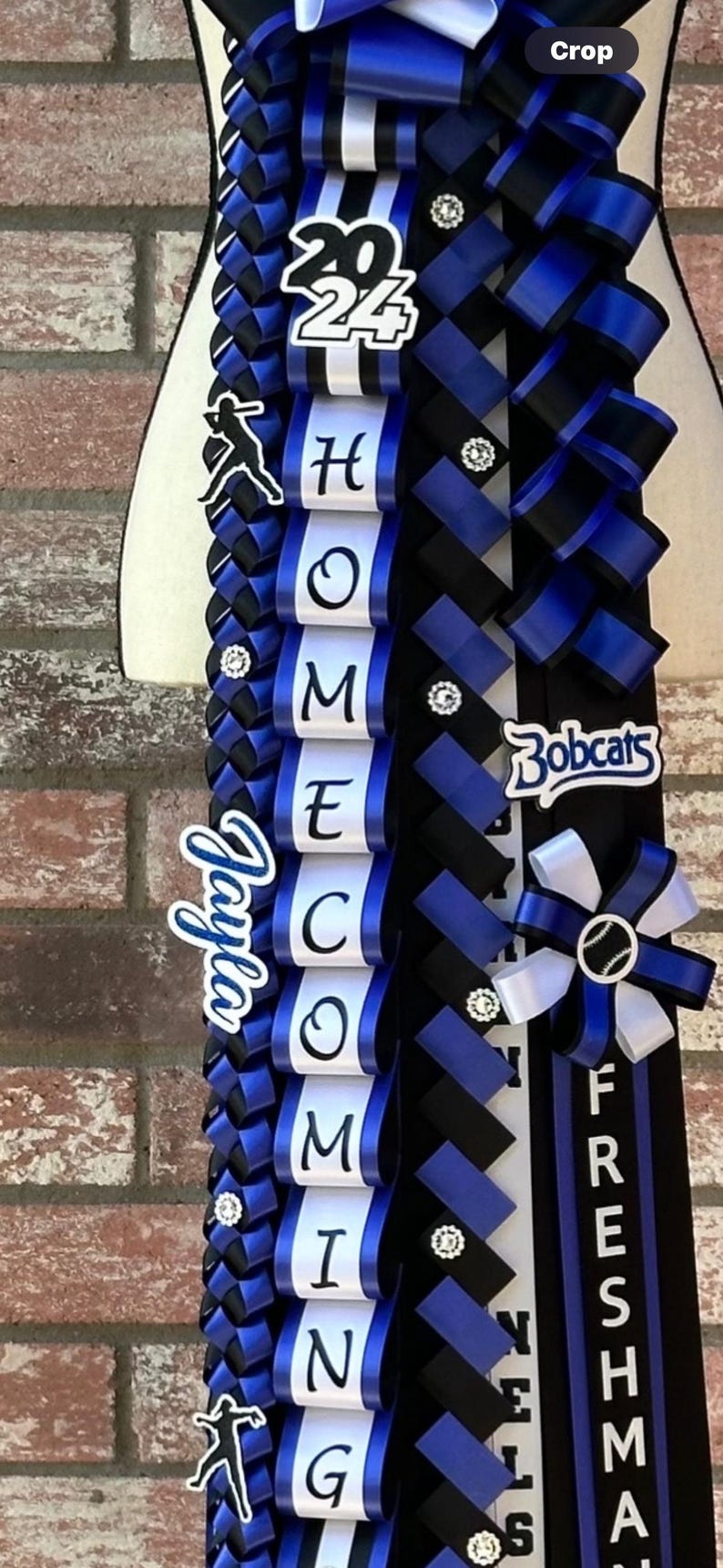 Pu&ograve; includere: Un mum di ritorno a casa blu e nero con nastri bianchi e un tema di baseball. Il mum presenta le parole "HOMECOMING", "2024", "Bobcats" e "Freshman". Il mum ha anche una silhouette di un giocatore di baseball e una palla da baseball.