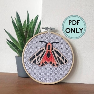 May include: A cross-stitch embroidery hoop with a black and red moth design on a white background with a floral pattern. The hoop is made of wood and has a natural finish. The text "PDF ONLY" is visible in the upper right corner of the image.