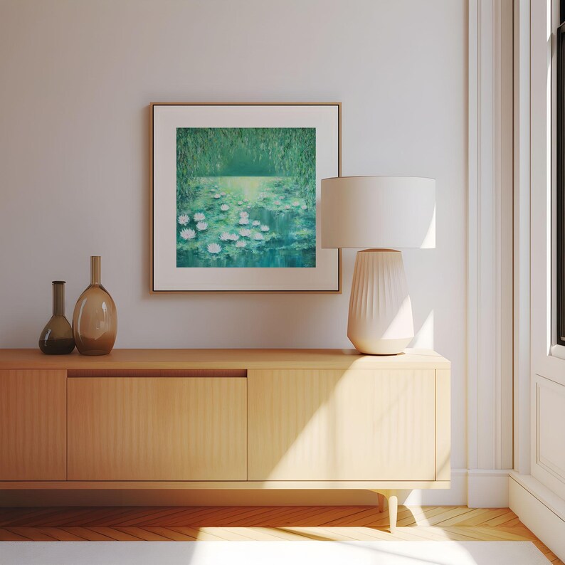 Puede incluir: Una pintura enmarcada de un estanque con nen&uacute;fares y follaje verde. La pintura est&aacute; colgada en una pared sobre un armario de madera con dos puertas.