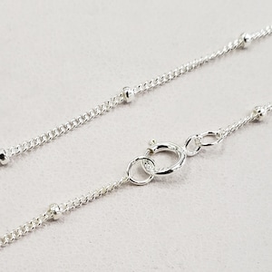 May include: A silver chain necklace with small round beads. The chain is delicate and has a lobster clasp.