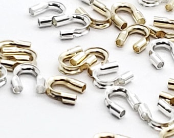 May include: A collection of gold and silver crimp beads, used for jewelry making. The beads are small and have a loop shape.