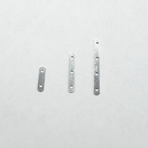 May include: Three silver metal strips with holes, the strips are different lengths.