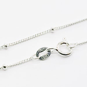 May include: A silver chain necklace with small round beads. The chain has a lobster clasp and a tag that reads "ITALY 925".