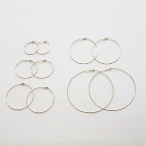 May include: Set of five gold hoop earrings in various sizes. The earrings are all simple and circular in shape.