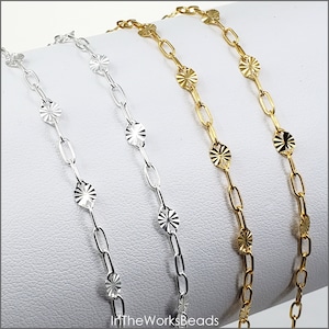 May include: Three silver and gold chains with decorative round links. The chains are displayed on a white surface.  In The Works Beads.