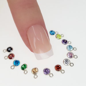 May include: Assortment of 12 small silver charms with colorful round gemstones. Each charm has a small loop for attaching to jewelry or other crafts.