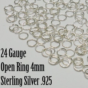 May include: A close-up of a pile of 24 gauge sterling silver open jump rings, each measuring 4mm in diameter. The rings are shiny and have a smooth finish.