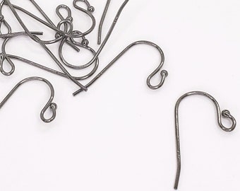May include: A pile of silver-toned earring hooks, scattered on a white surface.