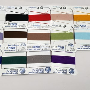 May include: A close-up of 12 spools of nylon thread for stringing beads and pearls. The spools are labeled "Nylon Power" and come in a variety of colors, including black, red, beige, yellow, purple, brown, green, blue, navy, dark green, gray, and purple.