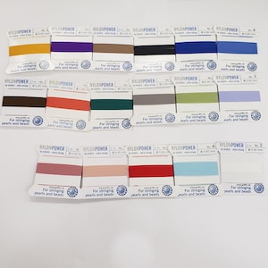 May include: Assortment of 2 meter spools of nylon thread in various colors, labeled "NYLONPOWER" for stringing pearls and beads. The spools are arranged in rows on a white surface.